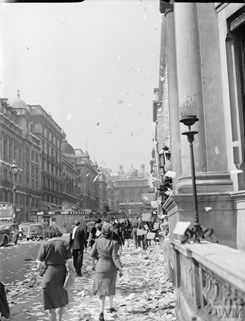Civilians walk amongst the piles of torn up paper which have been thrown, 'ticker tape'-style, from the windows of offices, on Lower Regent Street, London, to celebrate the signing of the Peace with Japan, 15 August 1945.
