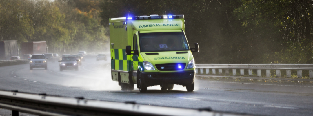 An ambulance driving along a wet road