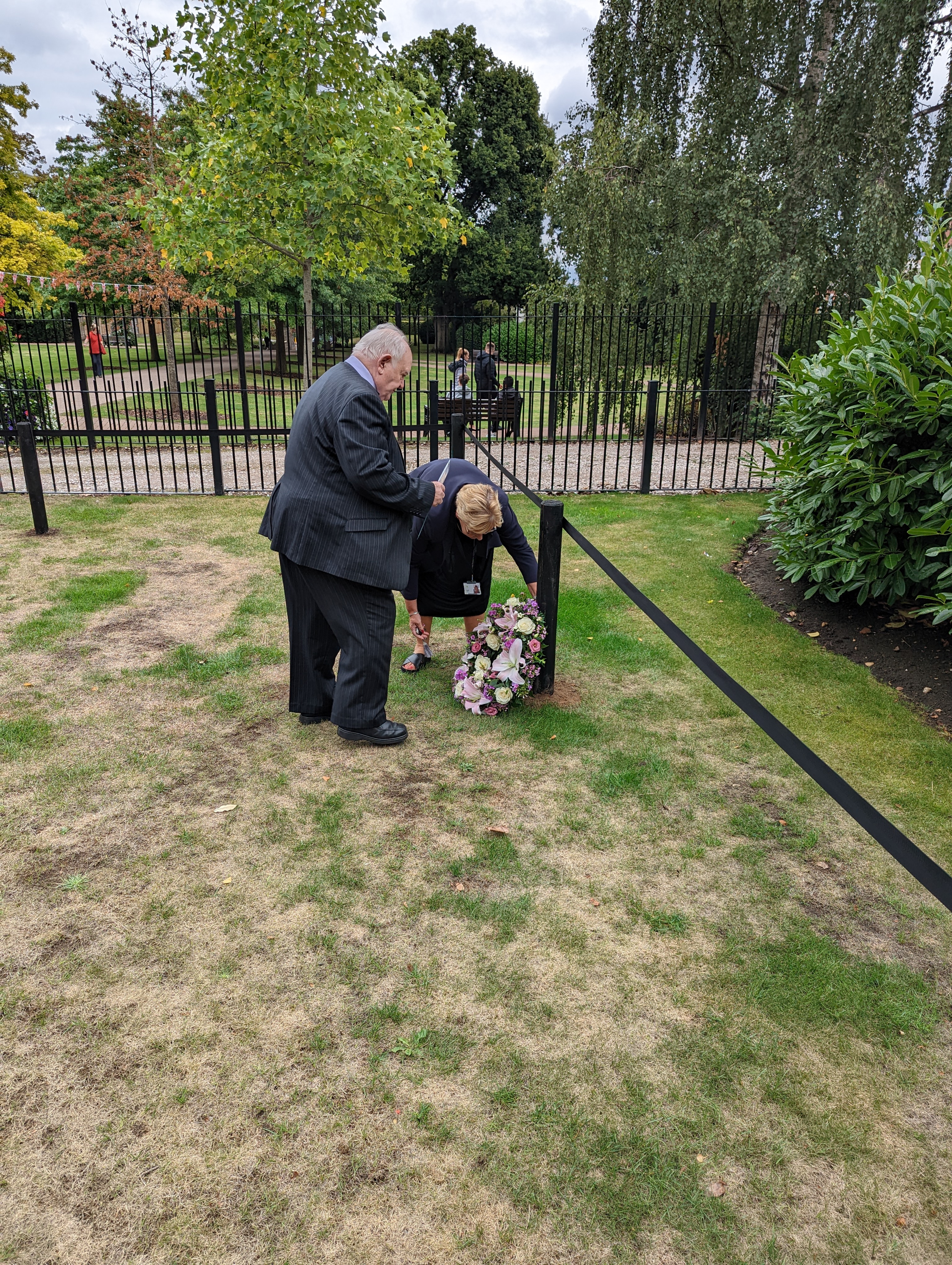 Image entitled Ashford Borough Council Leader Cllr Gerry Clarkson and Chief Executive Tracey Kerly laying the first floral tribute at the Memorial Gardens