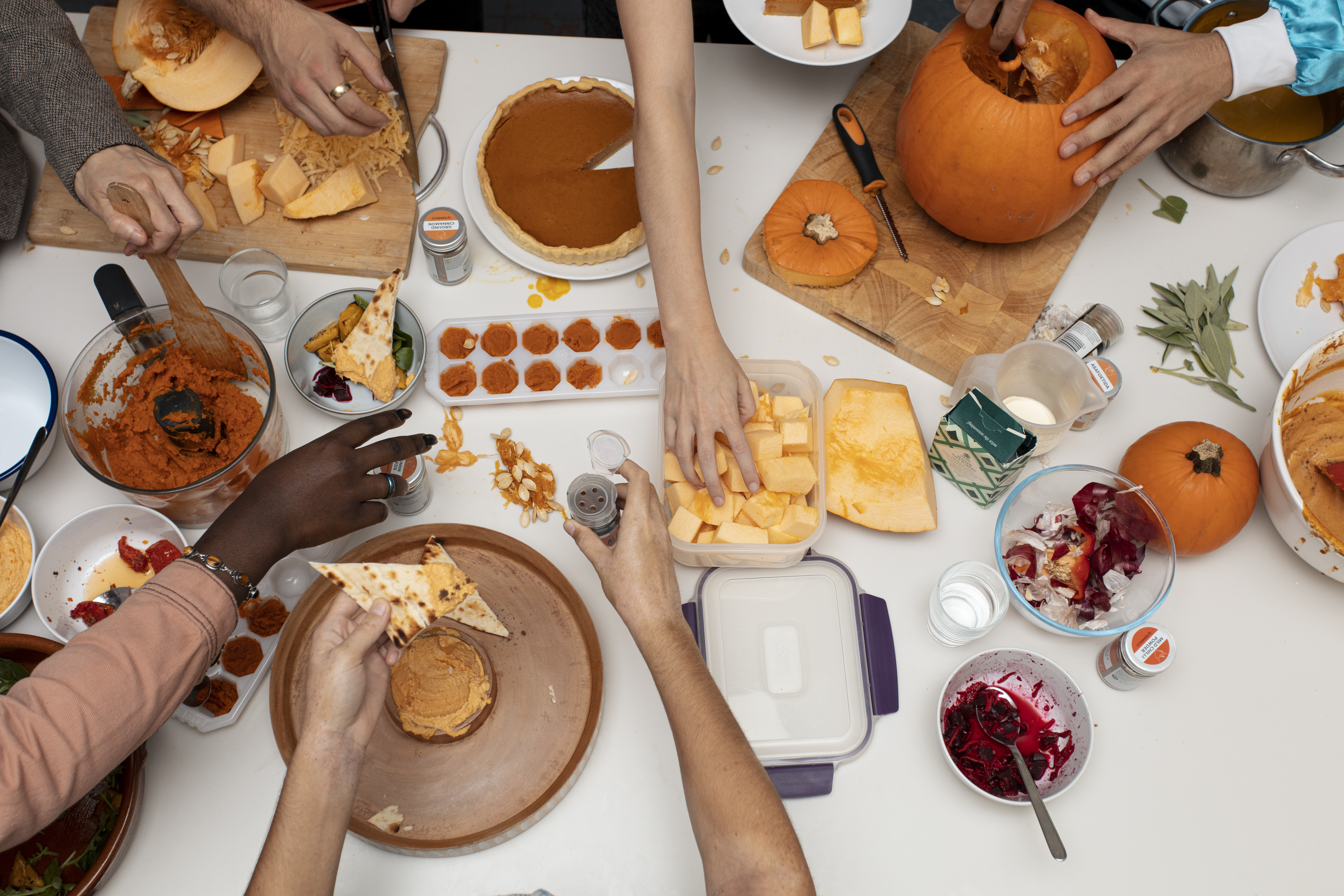 People eating off a table with lots of different style pumpkins dishes