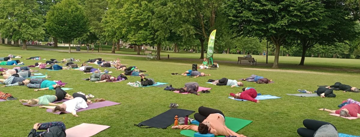 A group of people doing yoga on grass in a park