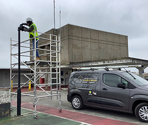 Image entitled Electrician Fixing A Car Park Light Next To An Electrical Services Van