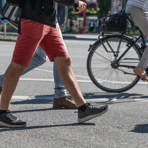 Image entitled A person walking with a person on a bicycle behind them.