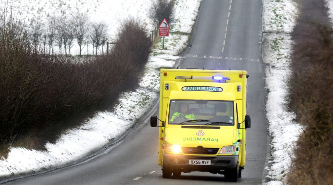 A photo of an ambulance driving in winter weather conditions