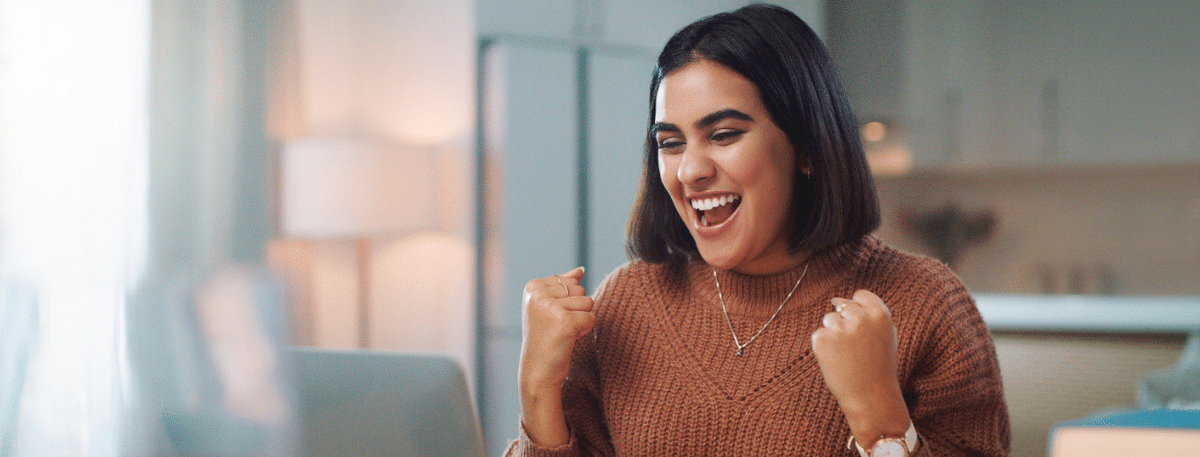 A woman looking at a screen and cheering with clenched fists