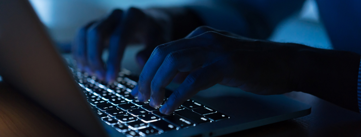 Person typing on a keyboard in the dark