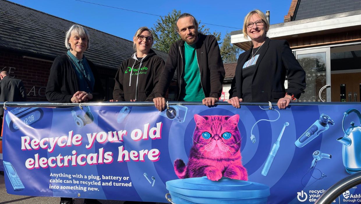 People standing behind banner that says Recycle your old electricals here 