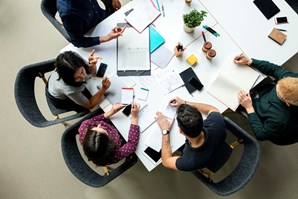 Aerial view of a boardroom with staff chatting and working around a table