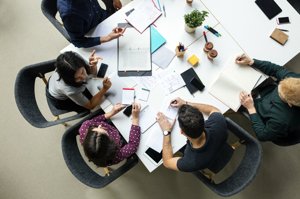 Aerial view of a boardroom with staff chatting and working around a table