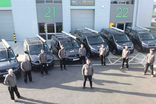 Fleet of Electrical Service Division vehicles, with electricians stood in front of their vehicles, looking up at the camera