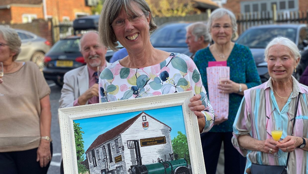 Debbie Greaves holding a painting of the museum