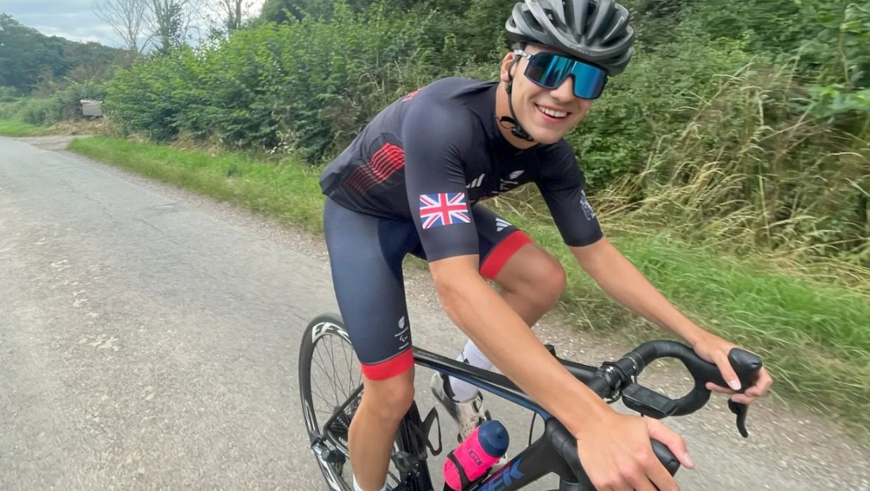 Image of a man cycling on a road wearing a helmet and Great Britain kit