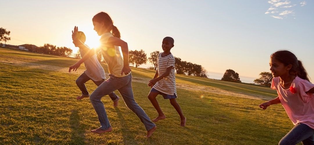 Four young children running together outdoors
