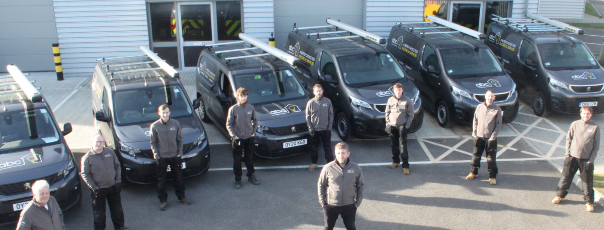 ABC Electrical Services team members taking a photo outside beside their vans
