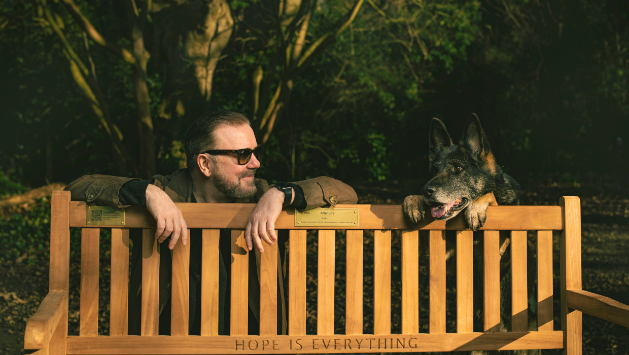 Ricky Gervais and his dog beside a bench to promote Netflix Hope is everything campaign tile