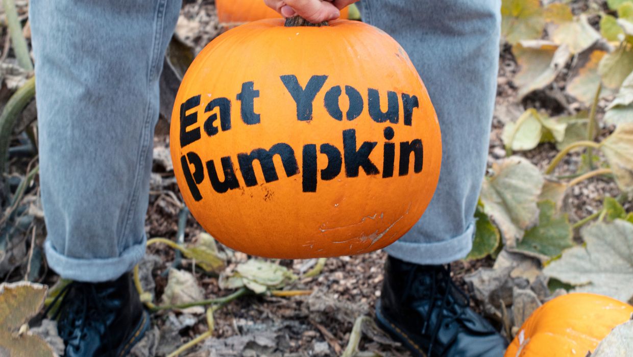 Someone holding a pumpkin with 'Eat your Pumpkin' written on it