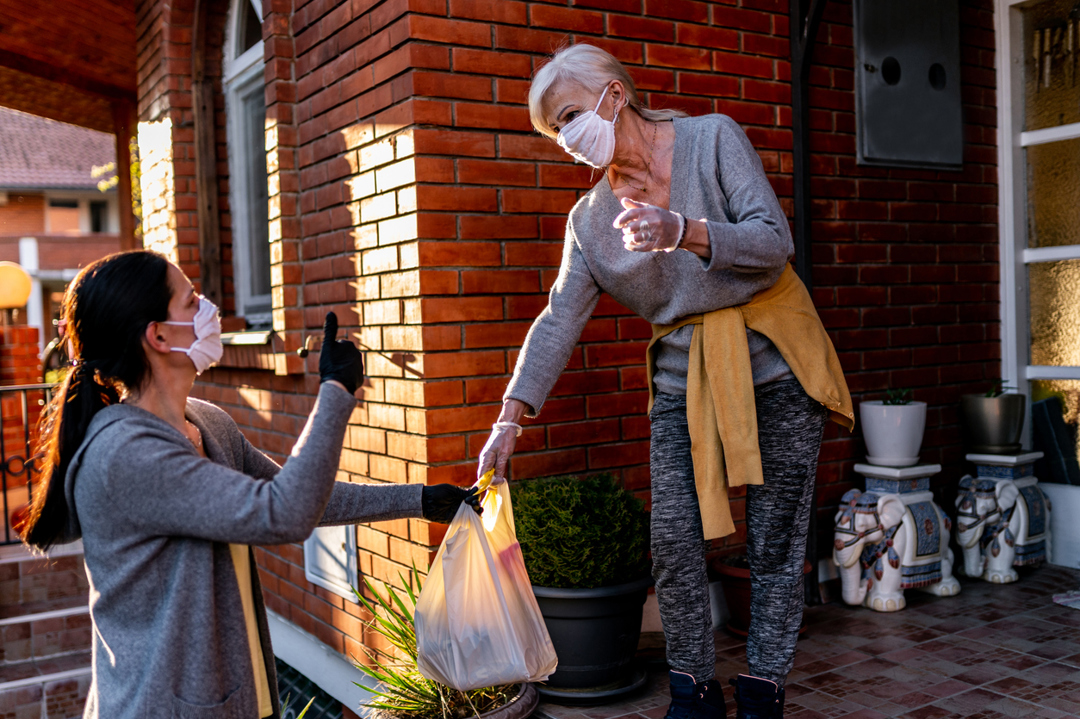 woman helping deliver groceries to a vulnerable person during lockdown whilst wearing a face mask
