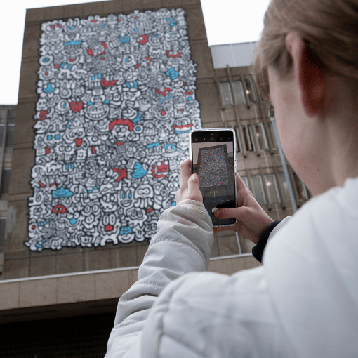 Image entitled A young person taking a photo of a mural in Ashford town centre