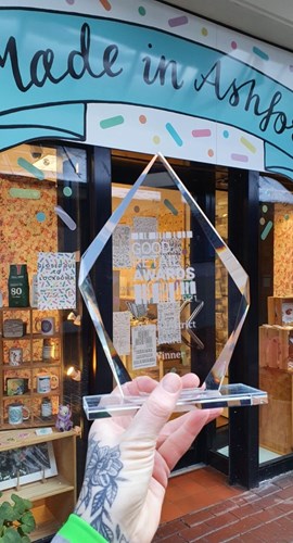 hand holding glass award in front of Made in Ashford shop