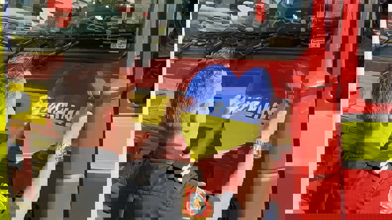 man putting a Ukraine heart sticker on a fire engine.jpg