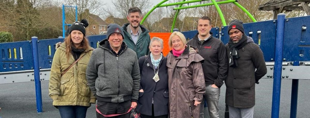 People standing in front of the new play equipment