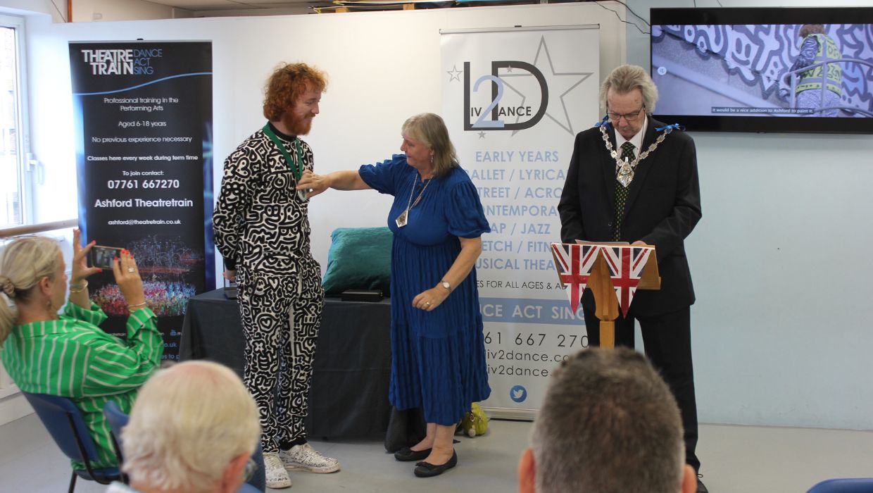 Mayoress Revd Dr Sue Starkings putting the award over Sam Cox ‘Mr Doodle’, with Mayor of Ashford Cllr Larry Krause