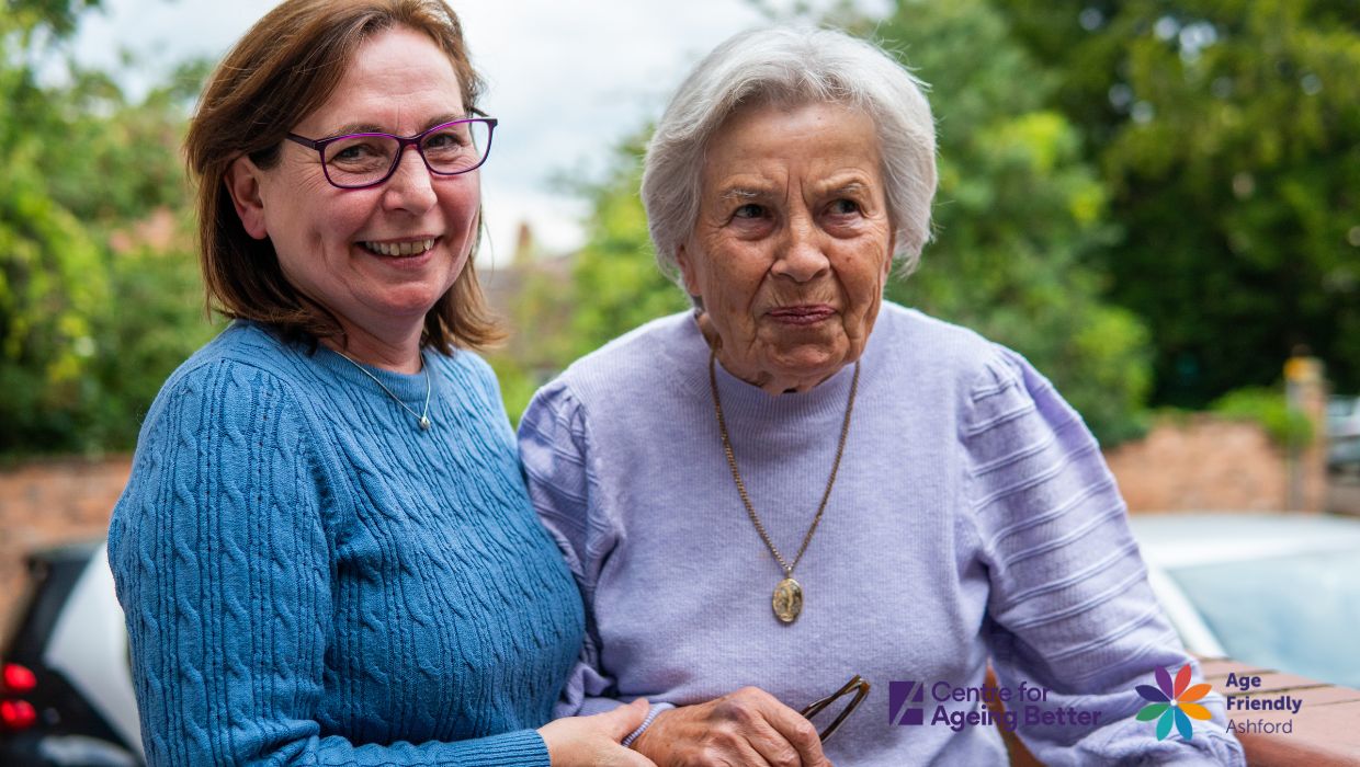 Two women over 50 smiling happily next to each other tile