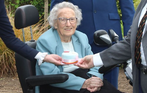 Mrs. Joyce Dawes receiving a surprise birthday cake during her 105th birthday tree planting and plaque ceremony in the Memorial Gardens, Ashford on 3 May 2022
